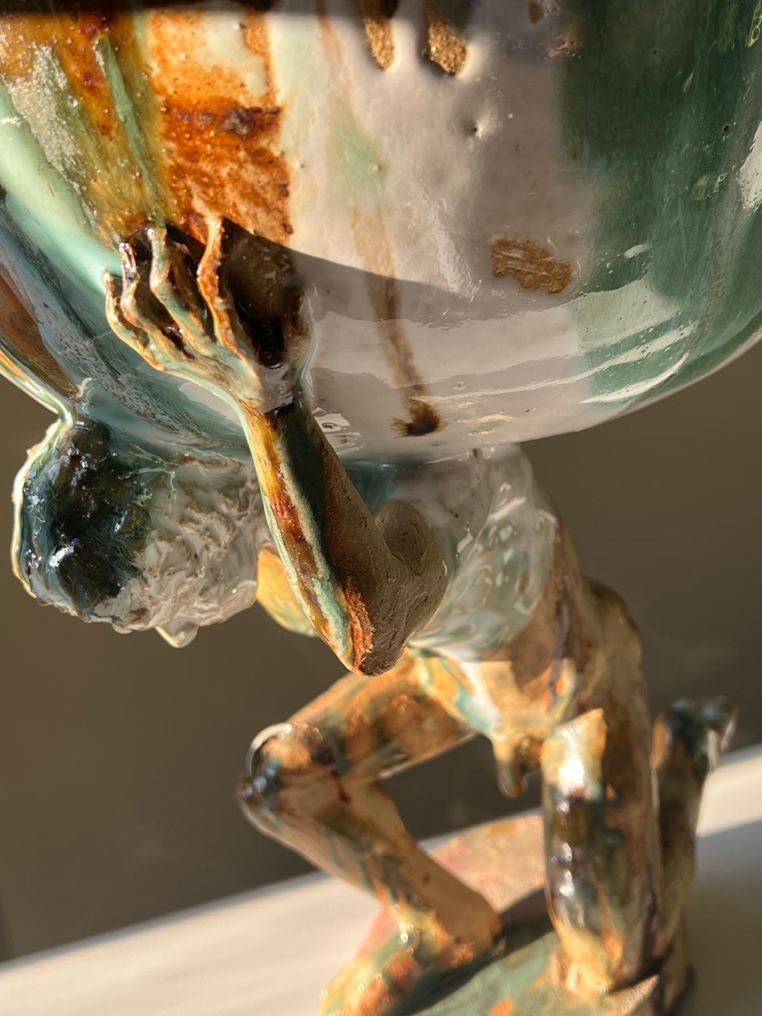 Détail d'une sculpture en grès, un Atlas portant le monde, coulures d'émaux maison inversées vers le haut